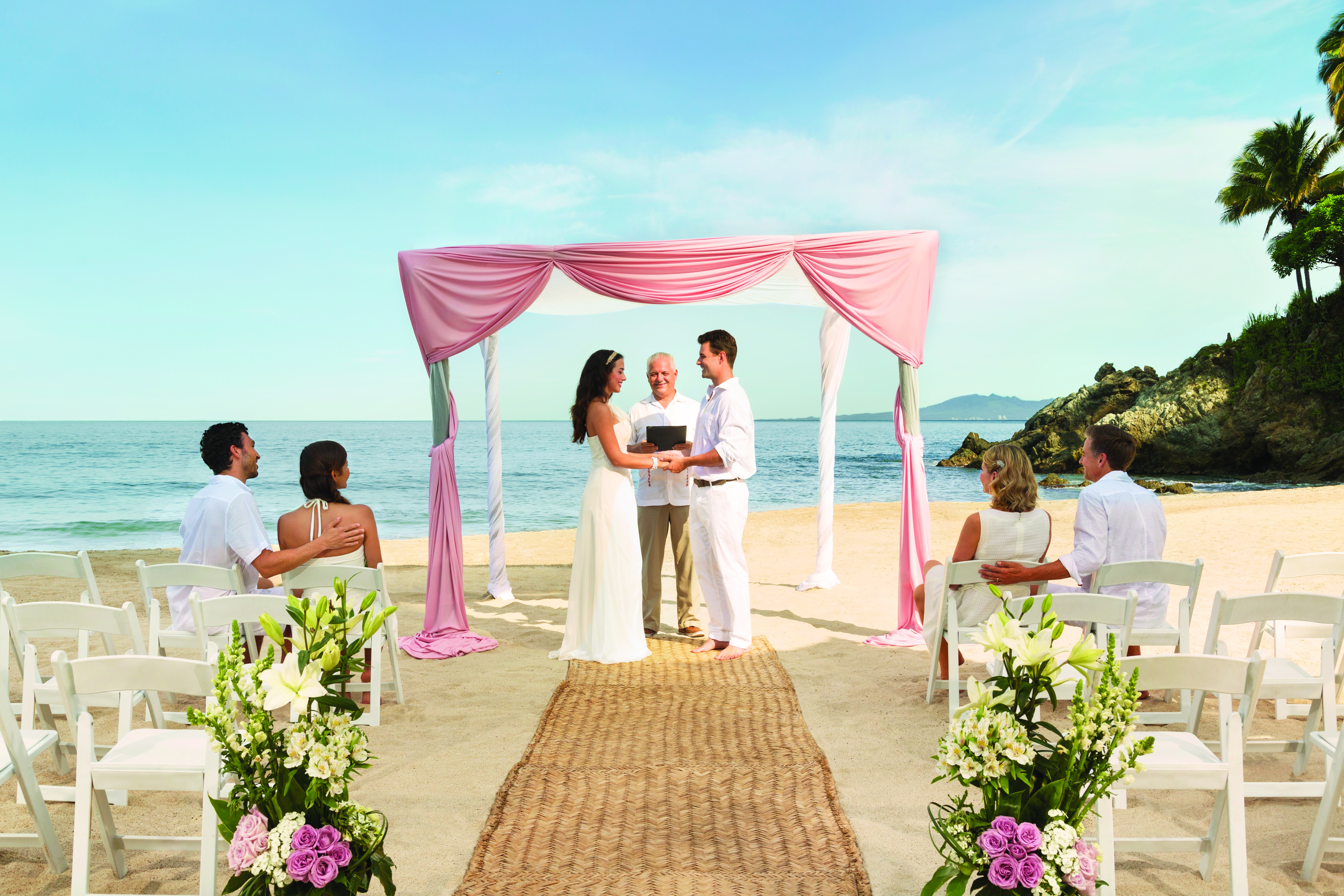 destination wedding, couple on beach, pink accent flowers and pink backdrop