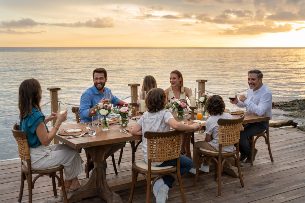 guests at table near beach with sunset